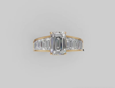 Diamond ring with emerald cut center stone and a gold band with tapered baguette diamonds